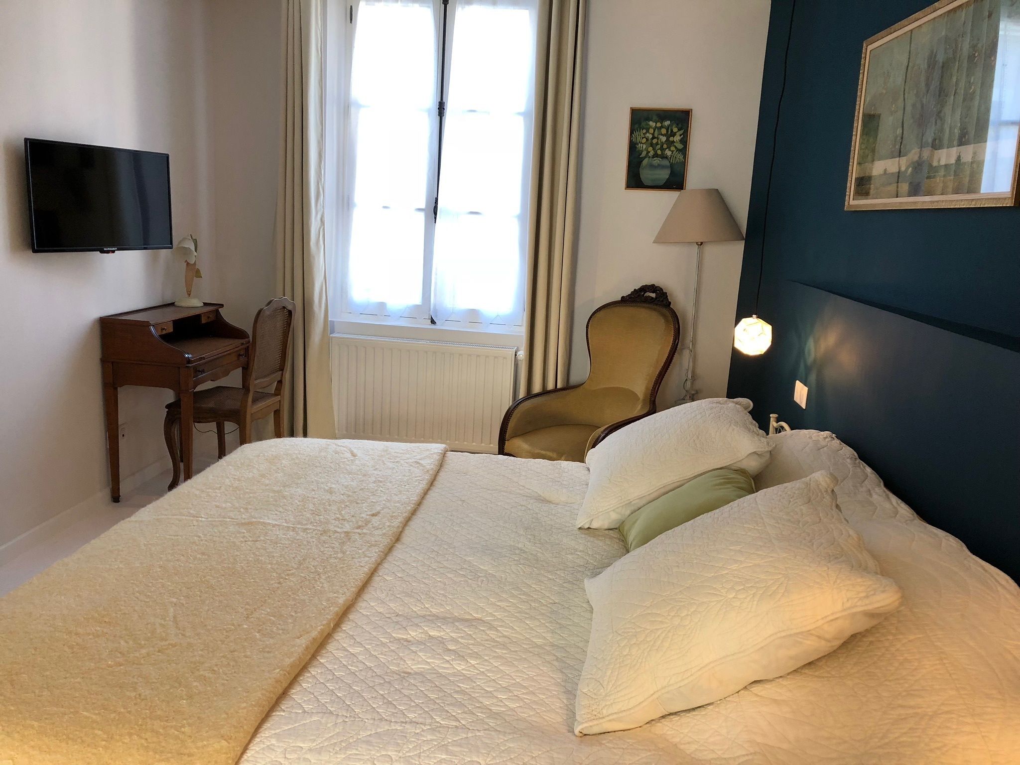 Une chambre d’hôtel avec un grand lit, un bureau, une chaise, une télévision et une fenêtre avec des rideaux.