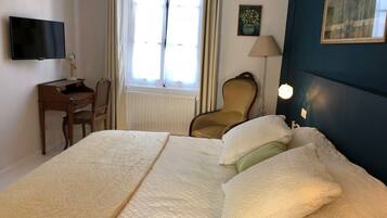 Une chambre d’hôtel avec un grand lit, un bureau, une chaise, une télévision et une fenêtre avec des rideaux.