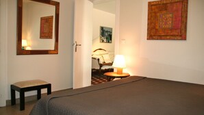 A bedroom with a bed, a bedside table, a chair, a lamp, and a mirror. - Nice house with great garden in Cap Ferret, center + bay + ocean on foot (Lège-Cap-Ferret)