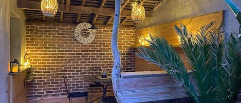 A cozy room with a brick wall, wooden ceiling beams, a wooden bench, and a large plant.