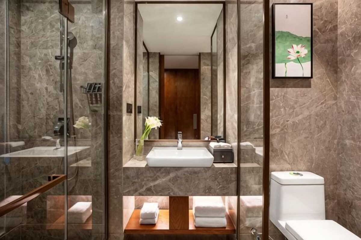 Un baño moderno con cabina de ducha de vidrio, lavamanos con espejo e inodoro.