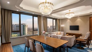 A hotel room with a large dining table, multiple chairs, a sofa set, and a TV mounted on the wall. - Ramada Encore by Wyndham Wuhan Caidian (Wuhan)
