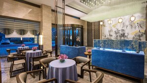 A modern hotel lobby with round tables, blue seating, and a decorative fountain. - Ramada Encore by Wyndham Wuhan Caidian (Wuhan)