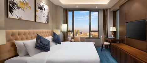 Quarto de hotel com uma cama grande, televisão, escrivaninha e vista da cidade.