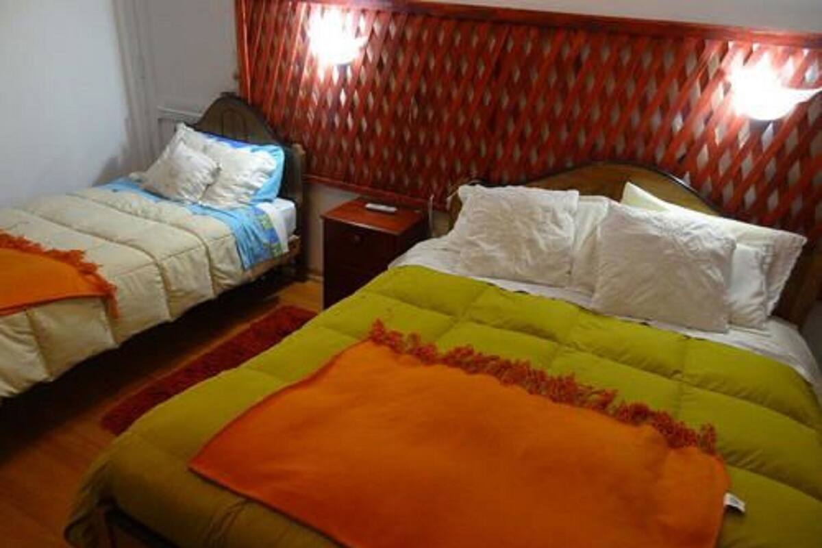 A bedroom with two beds, each with different colored bedding, a wooden headboard, and a small bedside table.