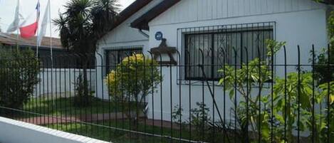 Un edificio blanco con techo negro, rodeado por una valla de metal.