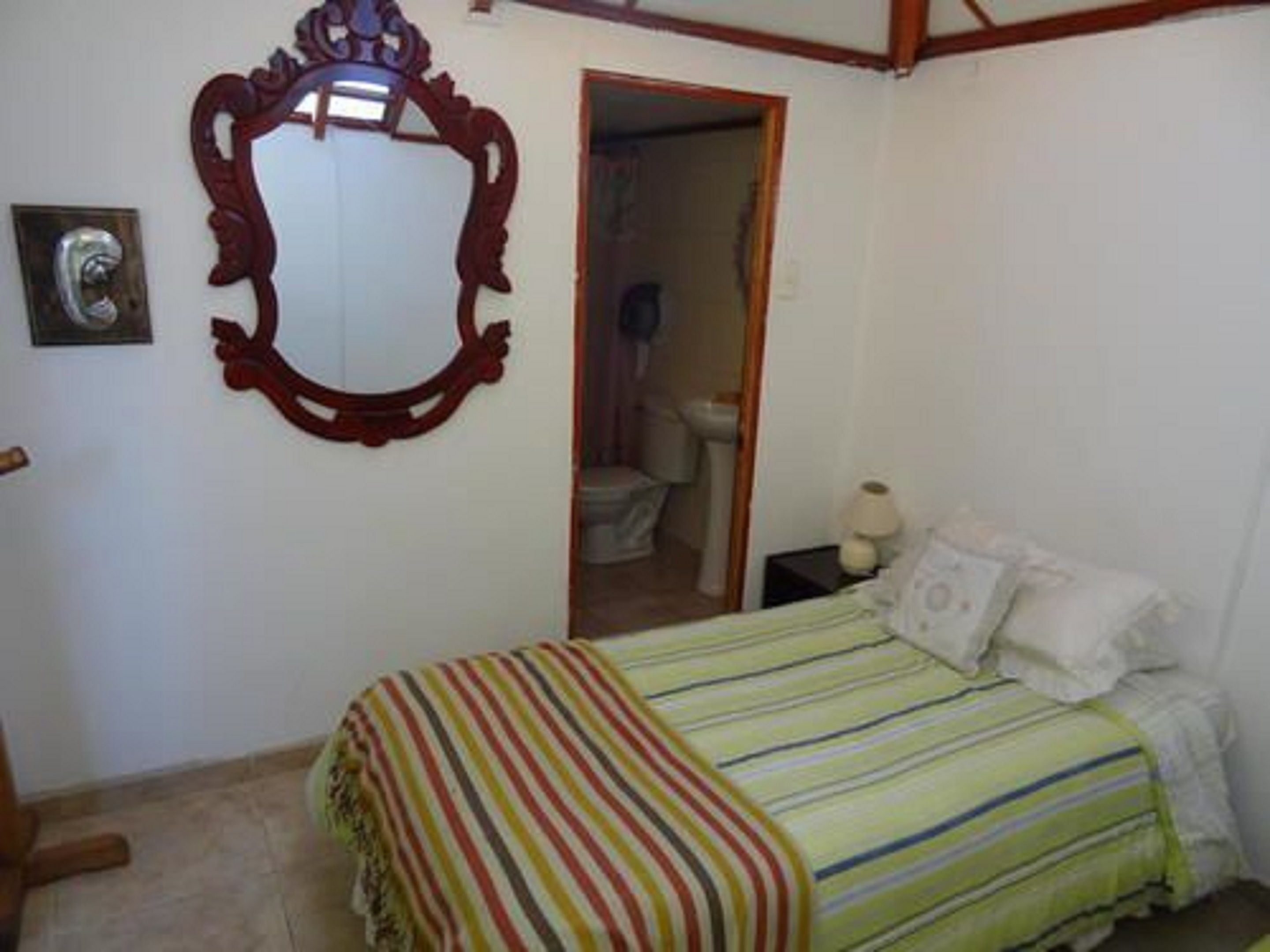 Un dormitorio con cama, un espejo y una puerta que da a un baño.