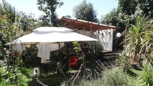 A garden with a white umbrella, a red chair, and various plants. - Hostal Vida 2000 (Santa Cruz)