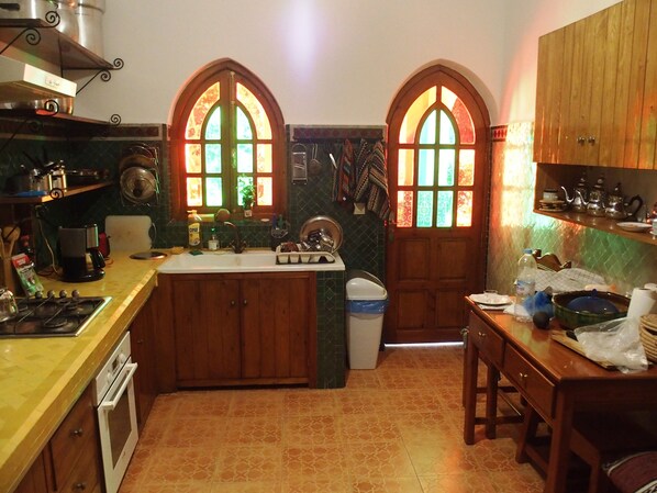 Uma cozinha com duas janelas em arco, fogão, forno, pia e armários de madeira.