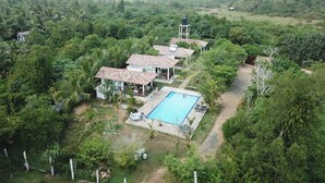 Una cabaña con piscina rodeada de abundante vegetación y un paisaje montañoso.