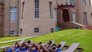 A castle-like building with a flag, a lawn with lounge chairs, and a clear sky. - Tafaria Castle (Ndaragwa)