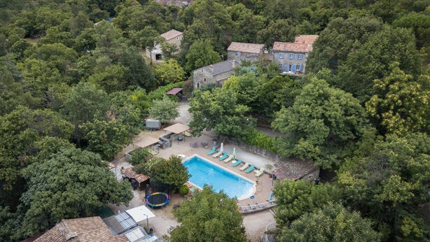 Ein Luftbild eines Anwesens mit Schwimmbad, Liegestühlen und Trampolin.