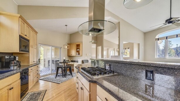 A modern kitchen with granite countertops, wooden cabinets, and a gas stove. - Larson Lane 217 - 4 Br Home (Frisco)