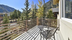 A balcony with a metal table and chairs, surrounded by trees and a mountain view. - Larson Lane 217 - 4 Br Home (Frisco)