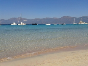 A beach with clear turquoise water and several sailboats anchored in the distance. - Nice studio, quiet, 2 minutes from the marina of St Florent. (Saint-Florent)