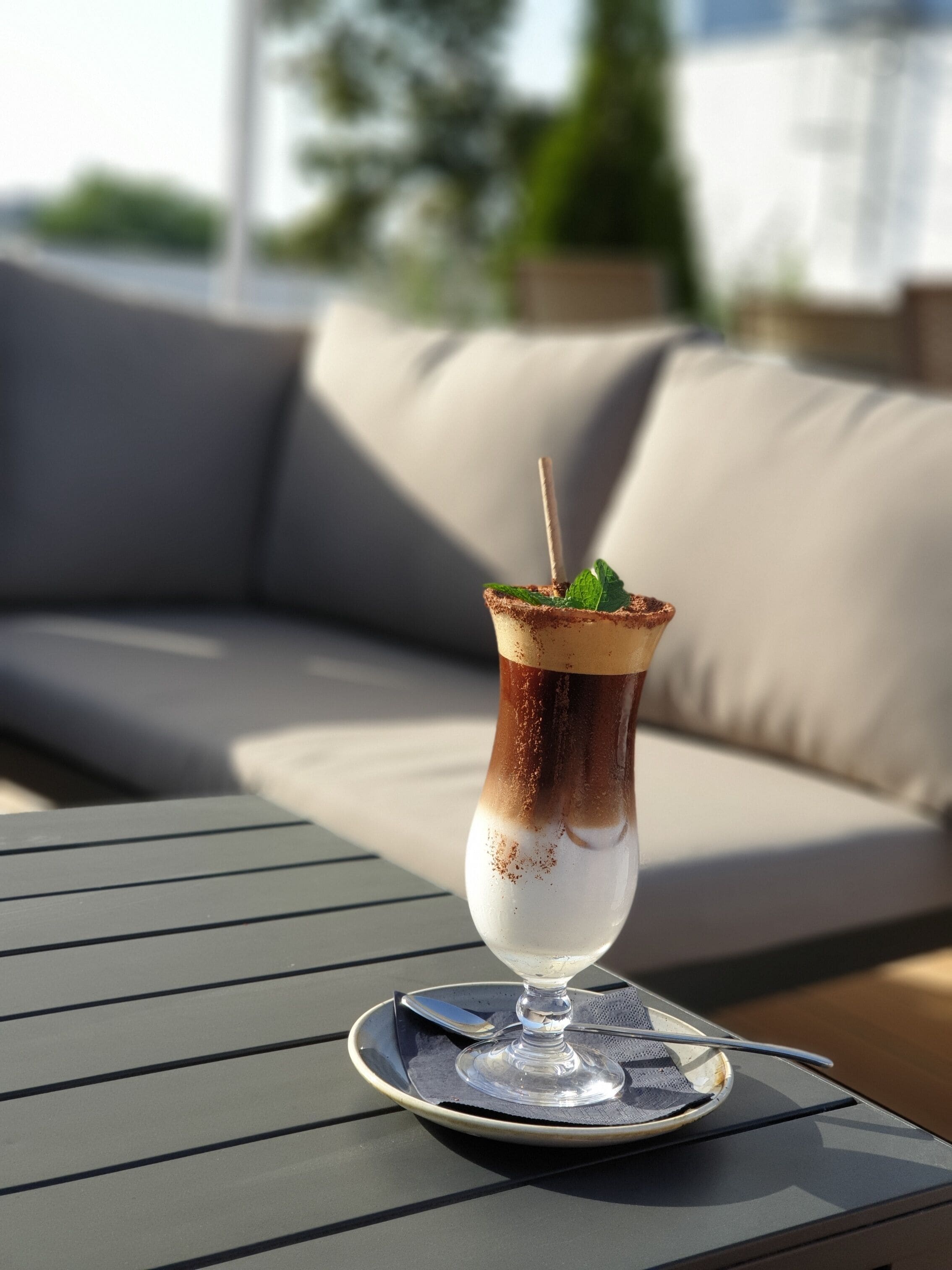 Un cocktail servi dans un verre, posé sur un dessous de verre, sur une table dont le cadre est en métal.