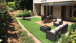A patio with outdoor furniture, a grill, and a stone wall.