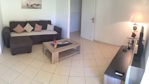 A living room with a sofa, a coffee table, a TV, and a lamp.
