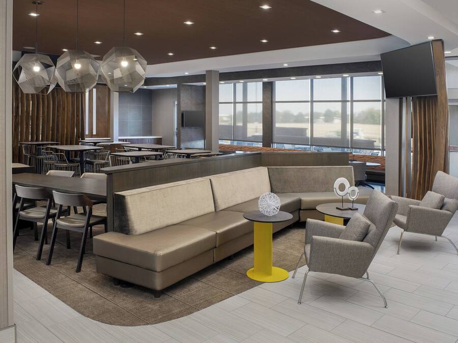 A modern hotel lobby with a seating area, a bar, and large windows.