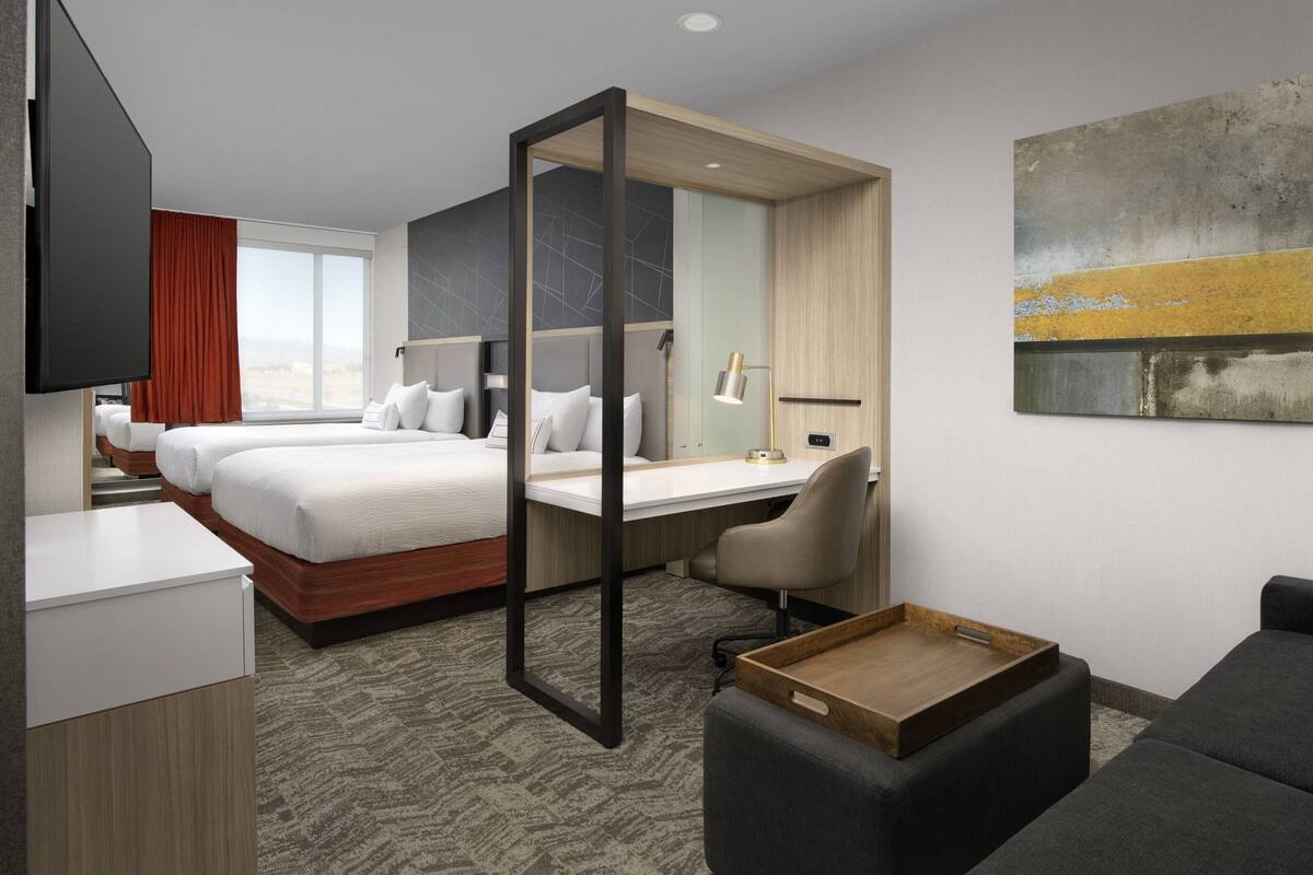 Una habitación de hotel con cama, escritorio, silla y televisor.