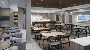 Un restaurant moderne doté de plusieurs espaces de restauration, notamment des tables rondes et des banquettes, ainsi qu’un bar.