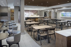 Un restaurante moderno con varias zonas de estar, incluyendo mesas redondas y cabinas, además de una barra.
