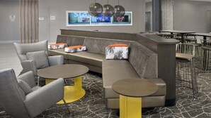 Un espace de détente moderne comprenant un canapé d’angle, des tables rondes et un bar.