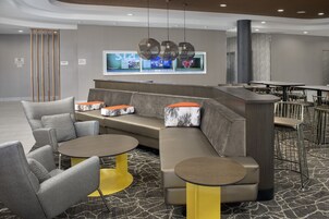 Un espacio lounge moderno con un sofá seccional, mesas redondas y una zona de bar.