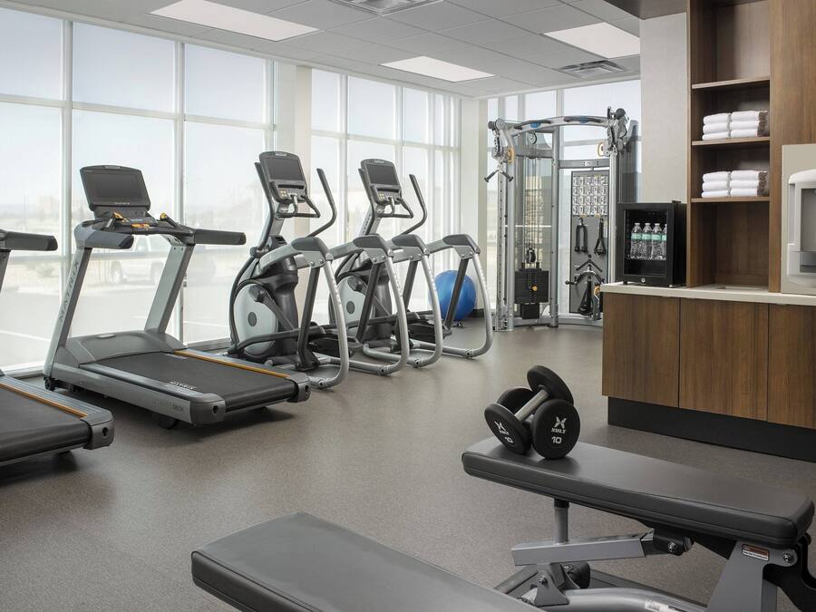 A gym with treadmills, elliptical machines, and weightlifting equipment.