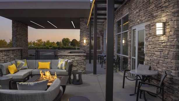 Une terrasse extérieure avec un mur en pierre, un foyer et du mobilier d’extérieur.