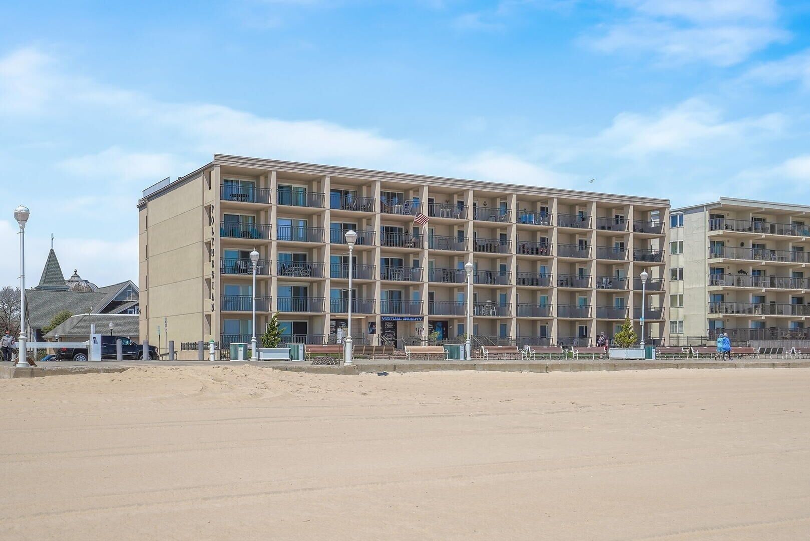 A multi-story hotel with balconies, a beach view, and a flag.