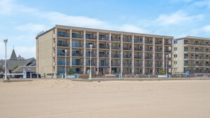 Ein mehrstöckiges Hotel mit Balkonen, Blick auf den Strand und einer Flagge.
