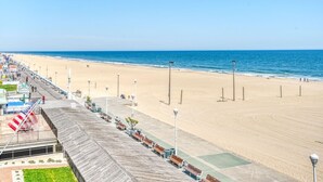 Ein Strand mit Promenadenweg, Bänken und Straßenlaternen.