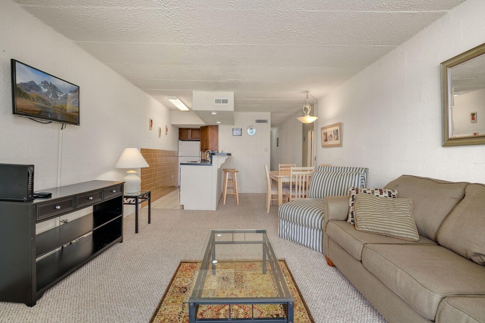 A compact living space with a kitchenette, a sofa, a coffee table, and a TV.