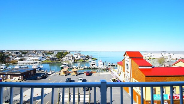 A marina with boats docked, a building with a red roof, and a clear blue sky.