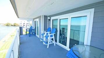 A balcony with a glass door, blue chairs, and a table.