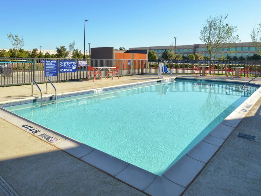 Piscina rectangular con borde de azulejos y una caseta de socorristas.