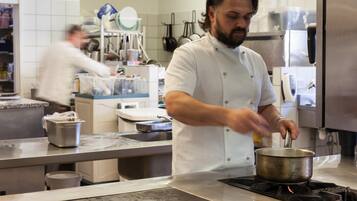 Un chef cocina en una cocina profesional con electrodomésticos y utensilios de acero inoxidable.
