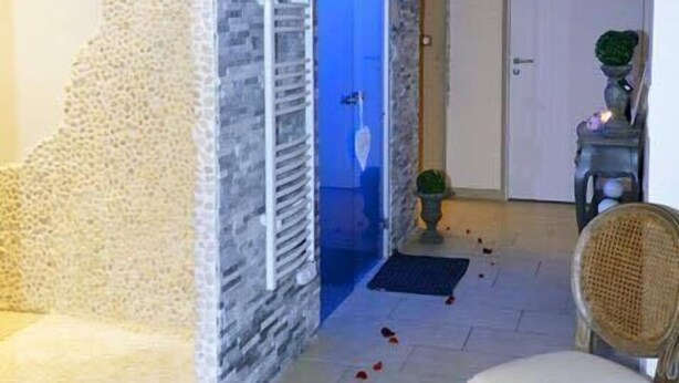 Habitació amb paret de pedra, làmpada de vimet, una cadira i una porta amb decoració de cor.