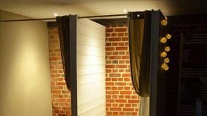 Una banyera d'hidromassatge amb il·luminació blava, una paret de maó i cortines.