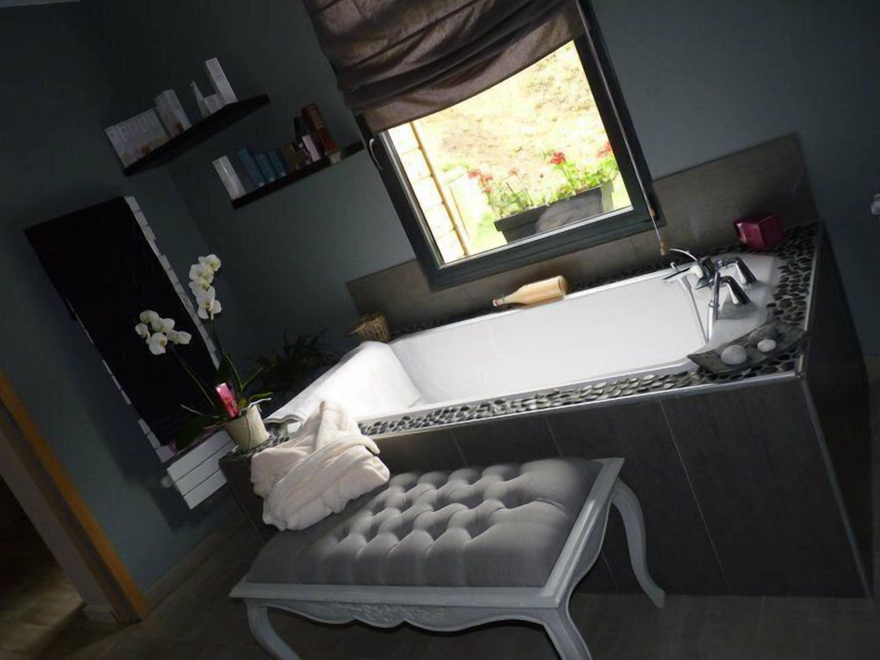 A modern bathroom with a freestanding bathtub, a vanity with a mirror, and a bench.