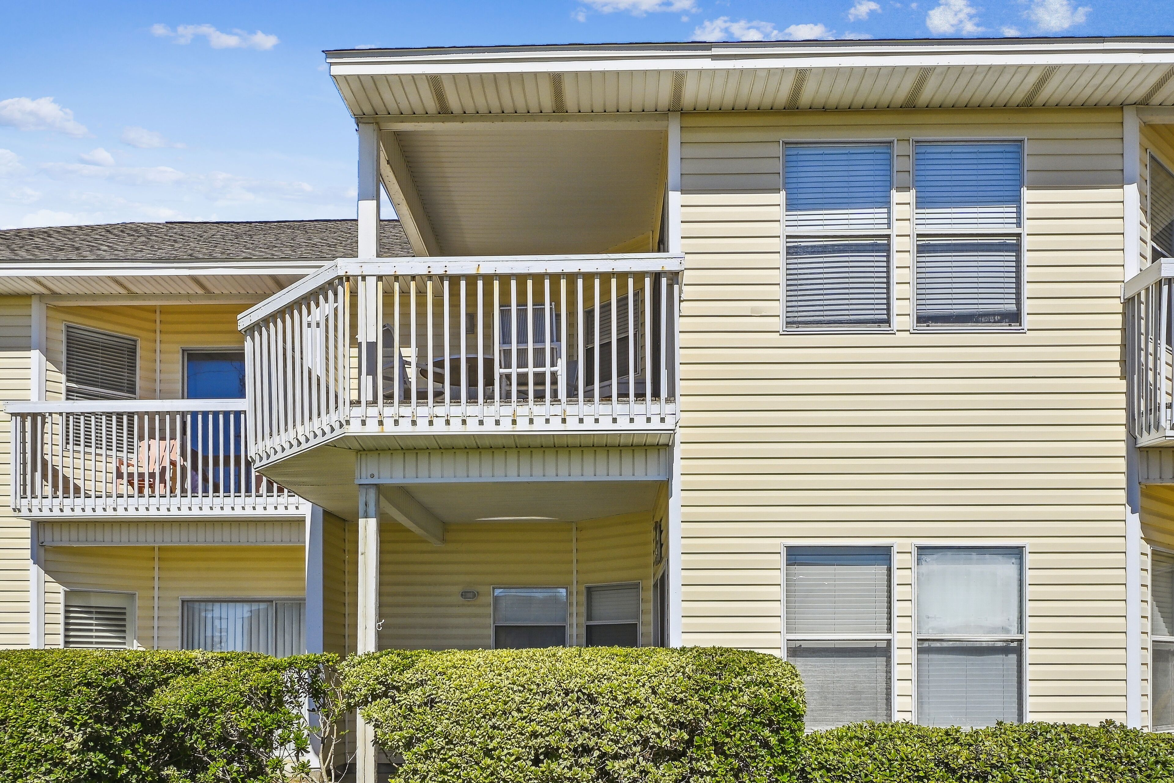 A multi-story residential building with balconies, large windows, and a flat roof.