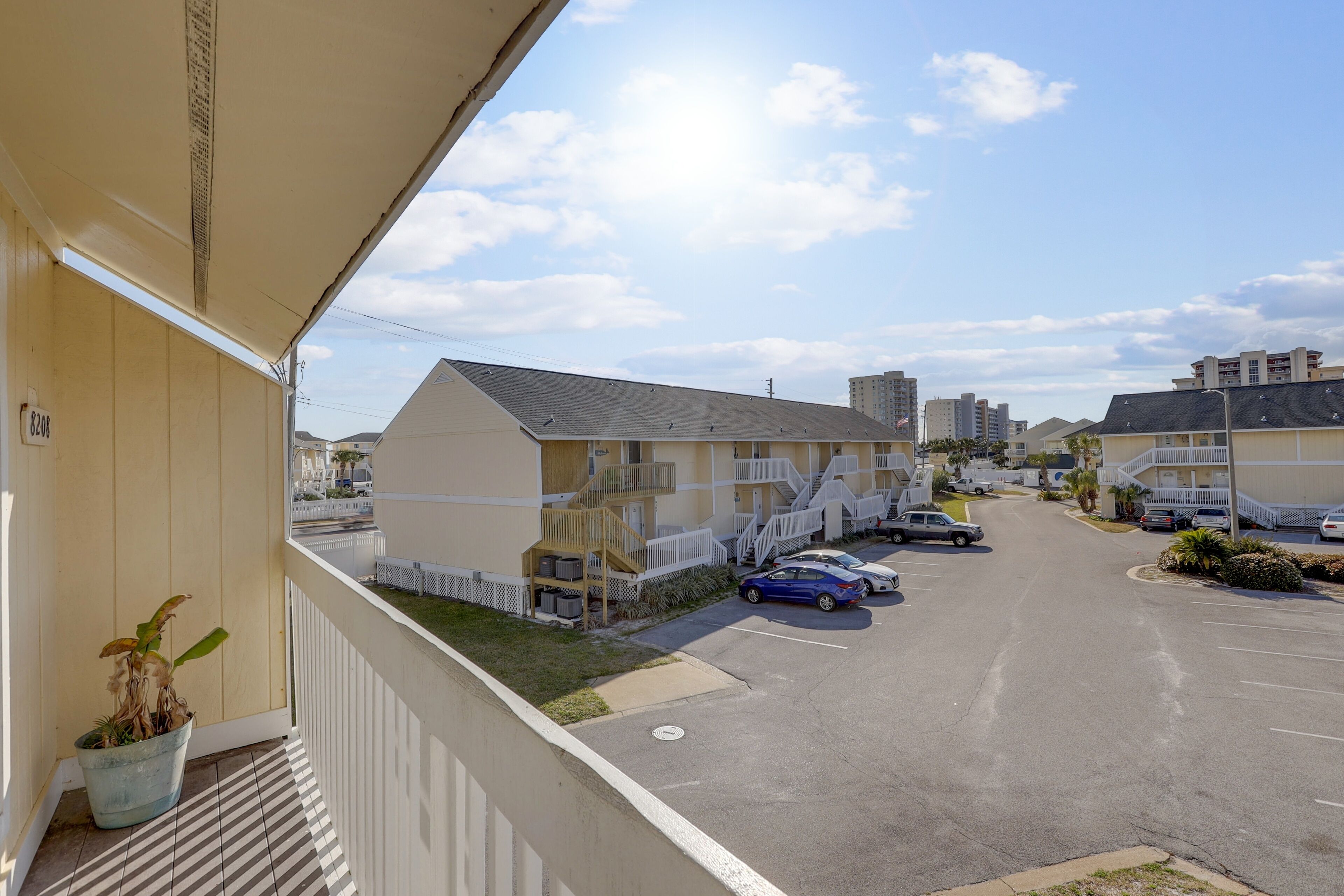 Un edificio residenziale con un parcheggio, una scala che conduce a un balcone e cielo sereno.