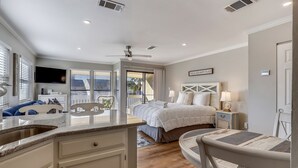 Une chambre moderne avec un grand lit, un ventilateur de plafond et une vue sur l’extérieur.