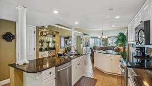 A spacious kitchen with a central island, white cabinetry, and a large window providing natural light.