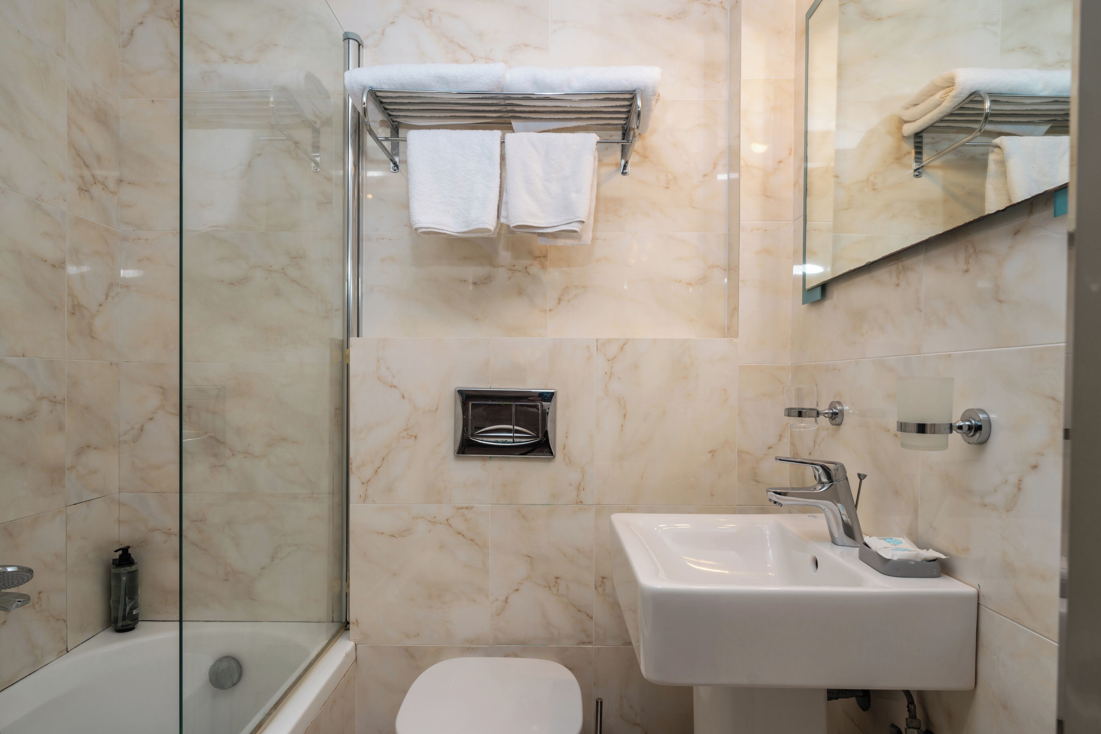 Un baño con cabina de ducha de vidrio, un lavamanos blanco y un inodoro.