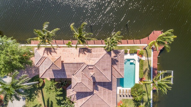 Vista aérea de un resort con piscina, palmeras y techo de tejas.