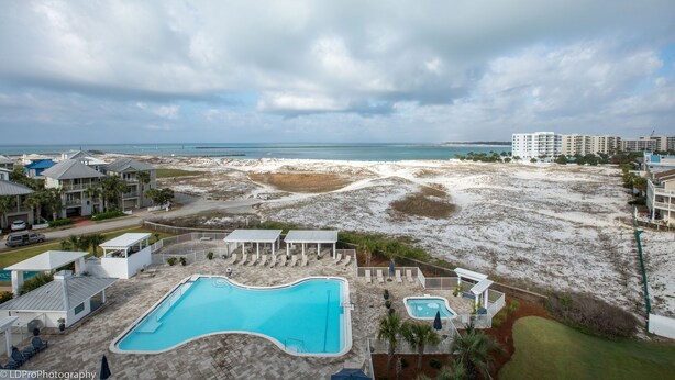 Een resort met een groot zwembad, uitzicht op het strand en meerdere gebouwen.