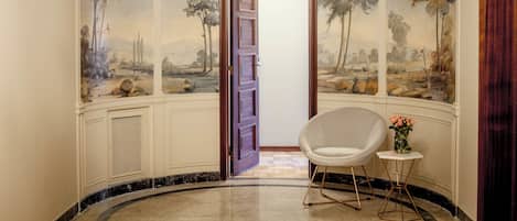 Una habitación con un mural de árboles y una puerta que da a otro espacio.