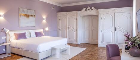 Un dormitorio con una cama grande, un armario blanco y un escritorio con una silla.